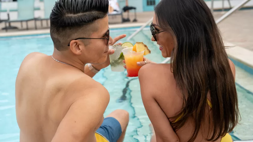 Picture of couple sharing drinks poolside