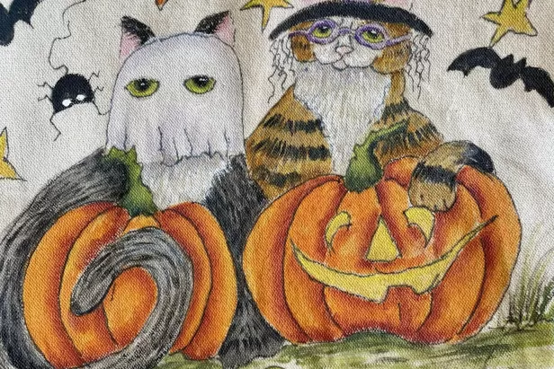 canvas bag painted with cartoon cats dressed as a ghost and a witch
